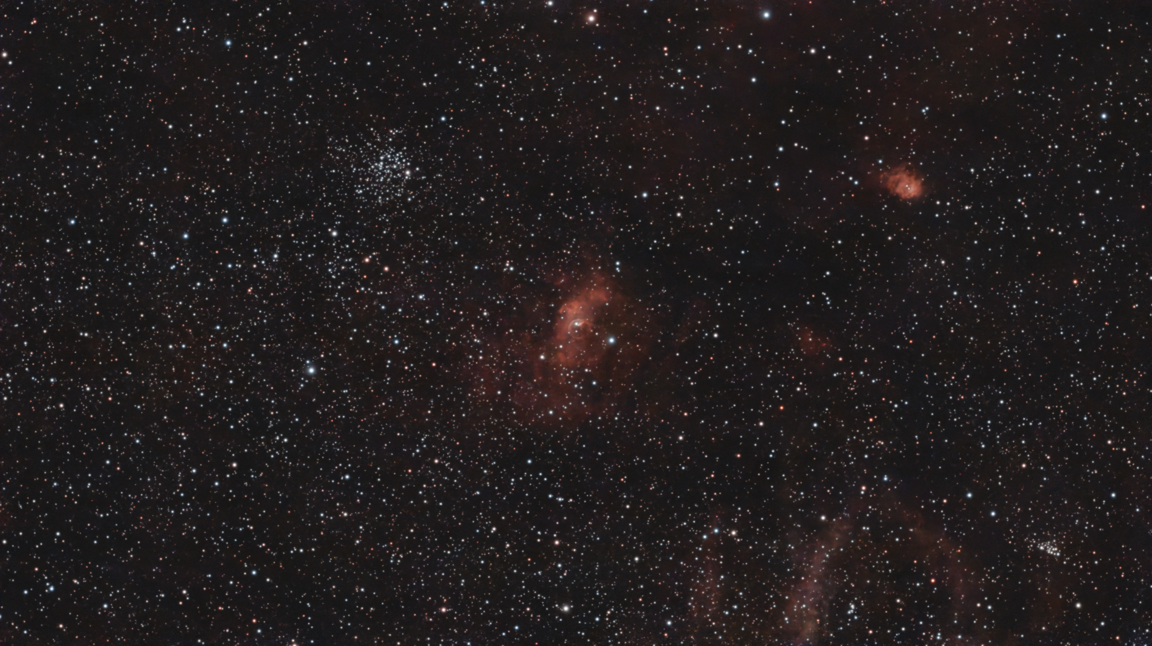 The Bubble Nebula's pale curved rim within red nebulosity, with the M52 star cluster above and to the left